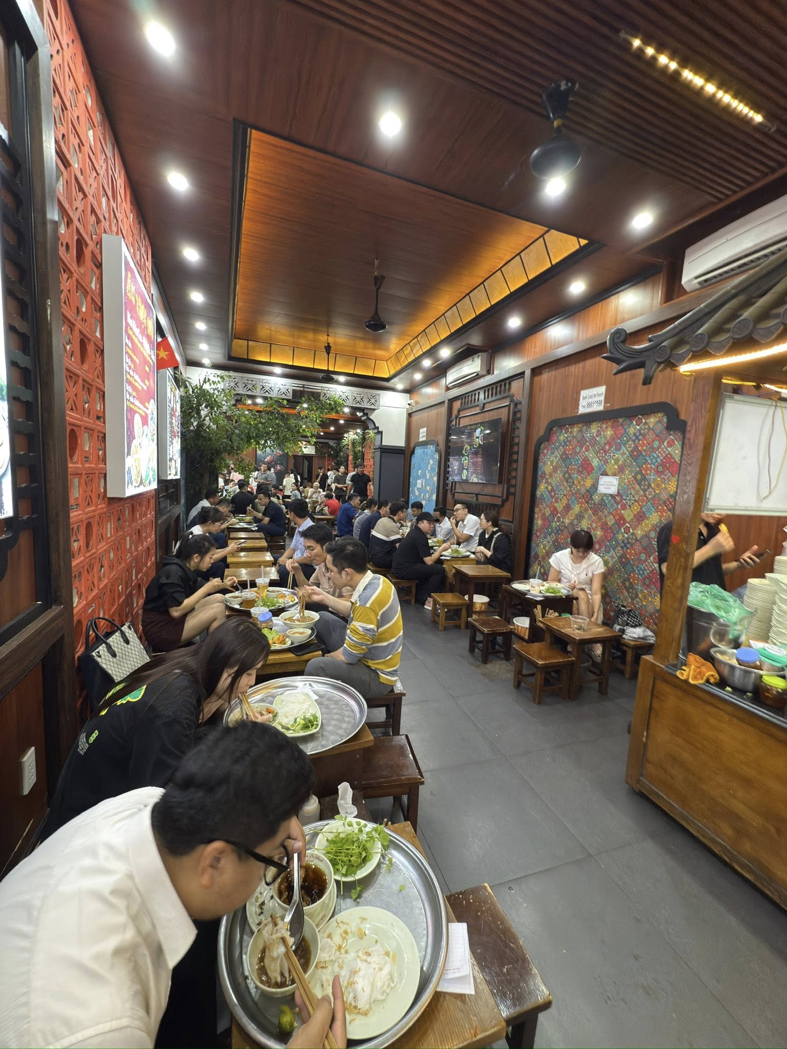 河內老城區街邊的粉卷小店門口,正值中午用餐時間,擠滿當地居民用餐的景象